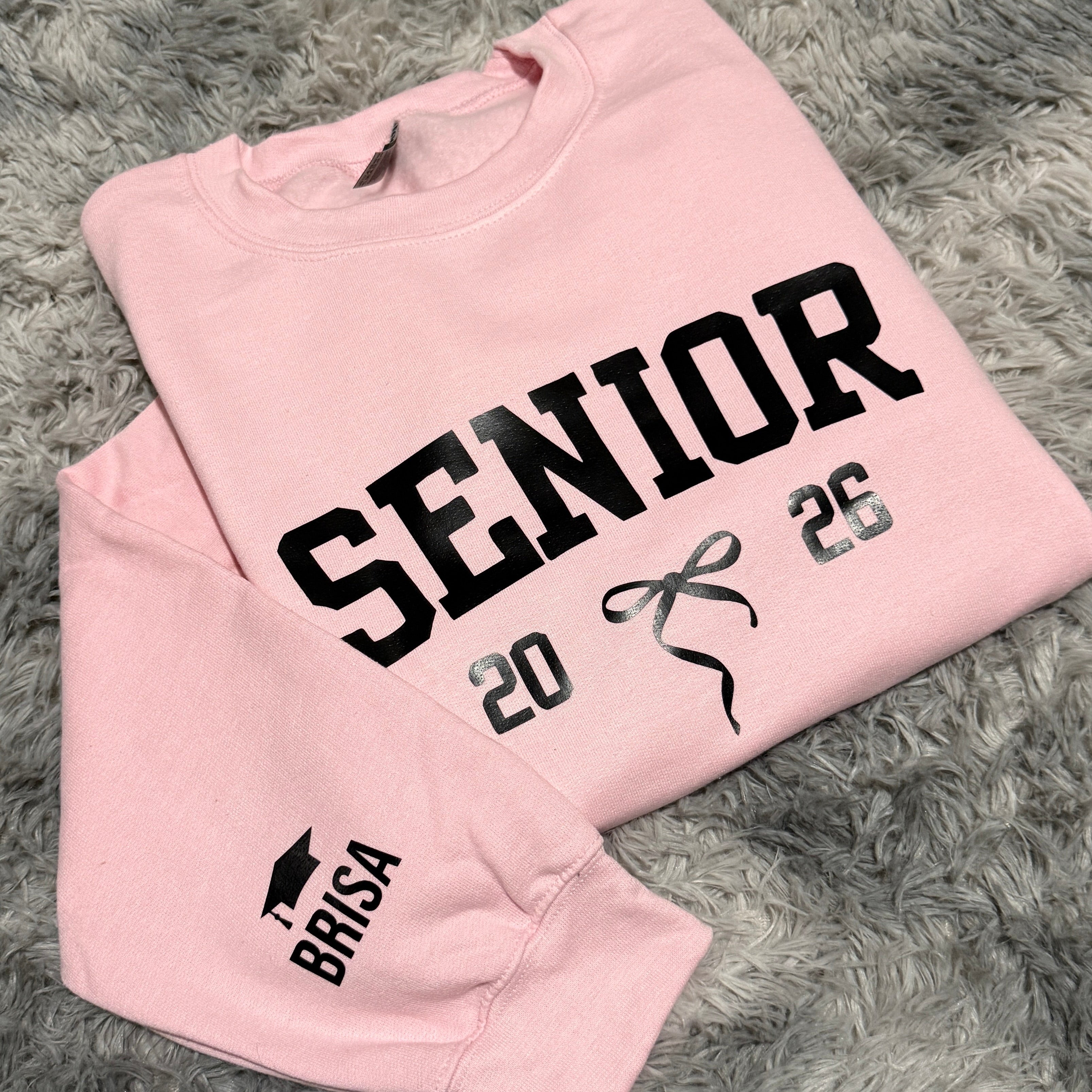 Pink sweatshirt with 'Senior 2025' text on a gray textured background